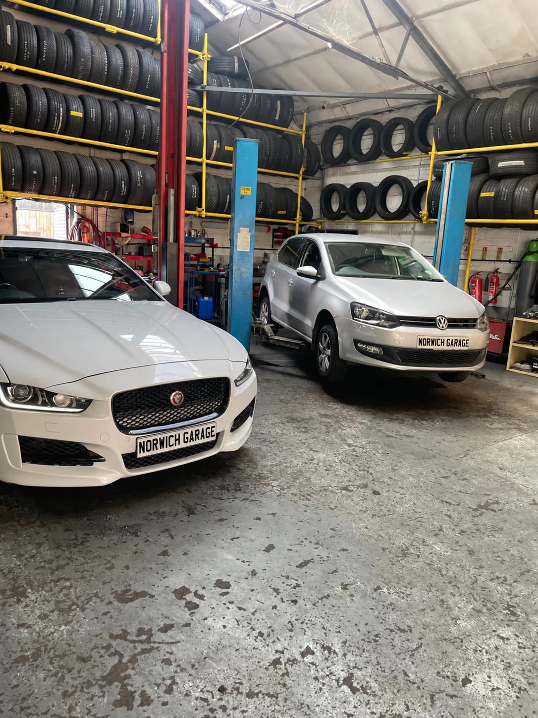 Two cars being serviced inside Norwich Garage